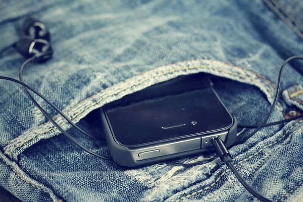Fone de ouvido e smartphone com jeans — Fotografia de Stock
