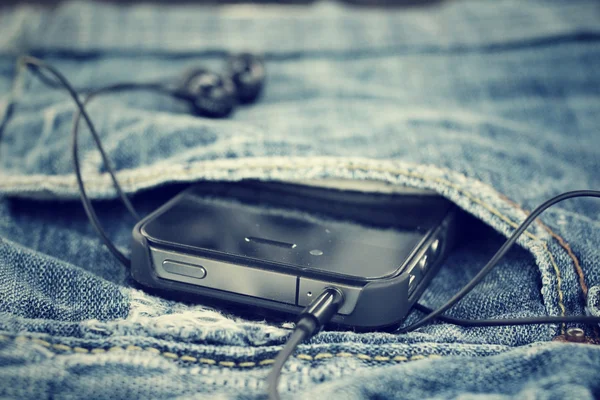 Oortelefoon en smartphone met jeans — Stockfoto