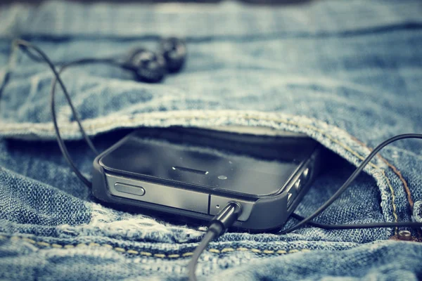 Auriculares y smartphone con jeans — Foto de Stock