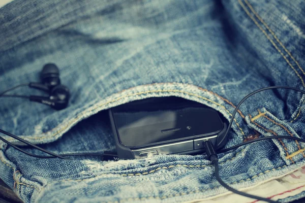 Fone de ouvido e smartphone com jeans — Fotografia de Stock