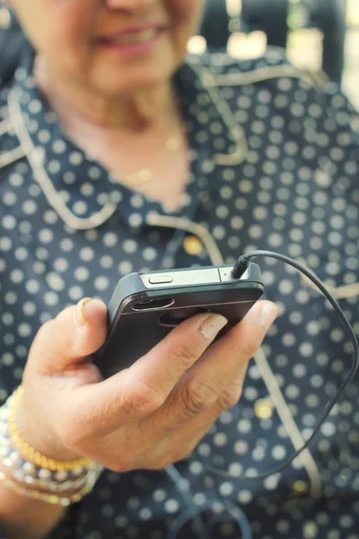 Senior listening to music on earphone with smart phone — Stock Photo, Image