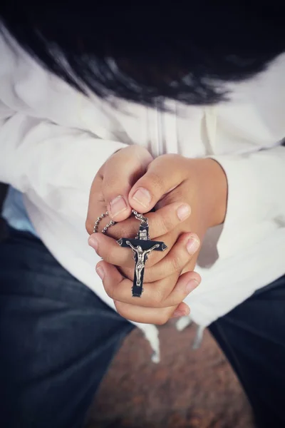 Hands praying with cross