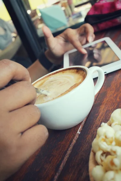 Жінка п'є чашку кави з планшетом в кав'ярні — стокове фото