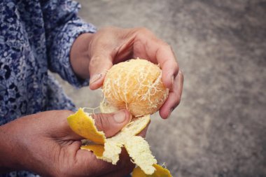 Senior woman eating orange fruit clipart
