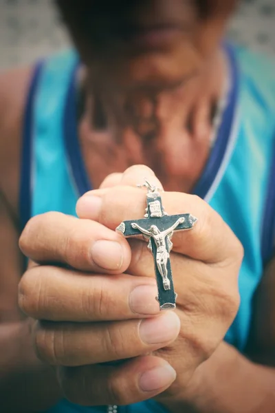 Senior man hands praying with cross