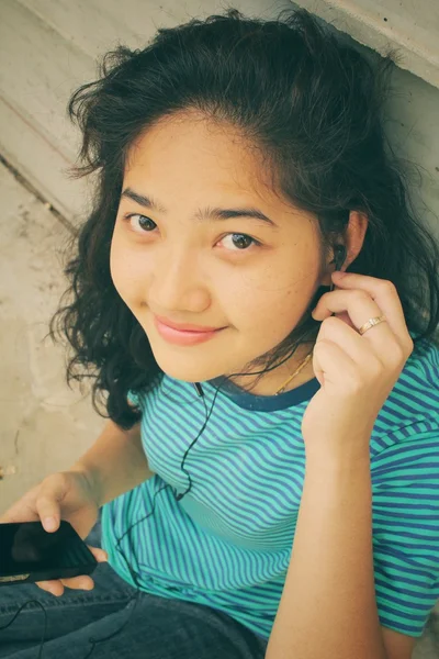 Jonge vrouw luisteren naar muziek op oortelefoon met slimme telefoon — Stockfoto