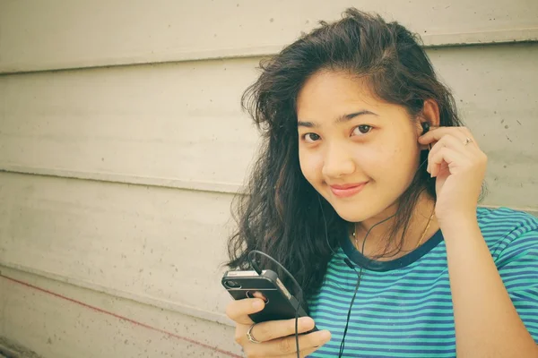 Young woman listening to music on earphone with smart phone — Stock Photo, Image