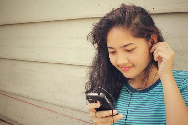 Jovem ouvindo música no fone de ouvido com telefone inteligente — Fotografia de Stock