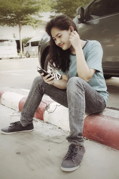 Молодая женщина слушает музыку в наушниках со смартфоном — стоковое фото
