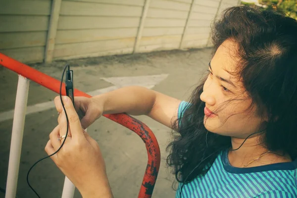 Mladá žena poslechu na sluchátka s Kobaltová modř telefon — Stock fotografie
