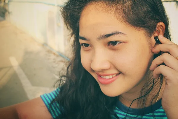 Mujer joven escuchando música en auriculares con teléfono inteligente — Foto de Stock