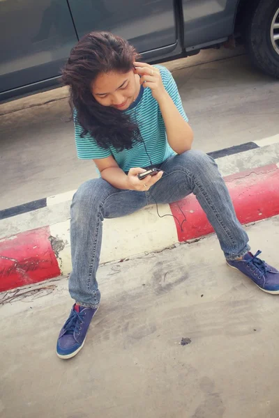 Mujer joven escuchando música en auriculares con teléfono inteligente —  Fotos de Stock