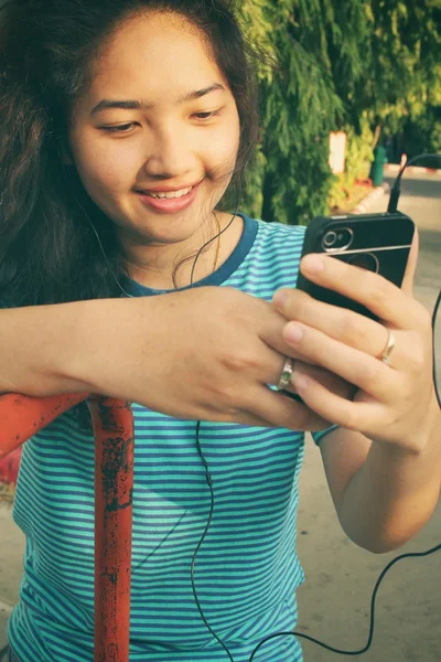 Ung kvinna lyssna på musik på hörluren med smart telefon — Stockfoto