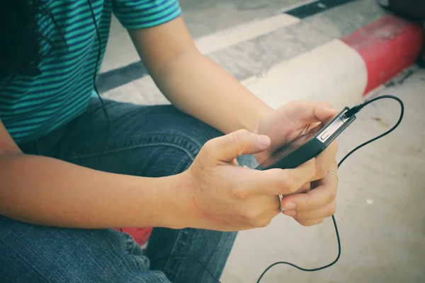 Mujer joven escuchando música en auriculares con teléfono inteligente — Foto de Stock