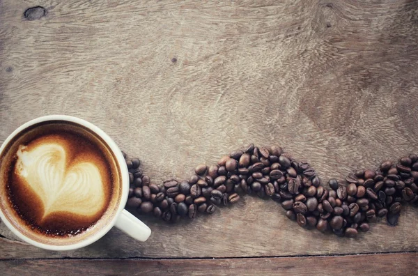 Vintage latte art coffee with beans — Stock Photo, Image