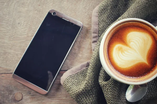 Latte starodawny sztuka kawy z inteligentny telefon — Zdjęcie stockowe