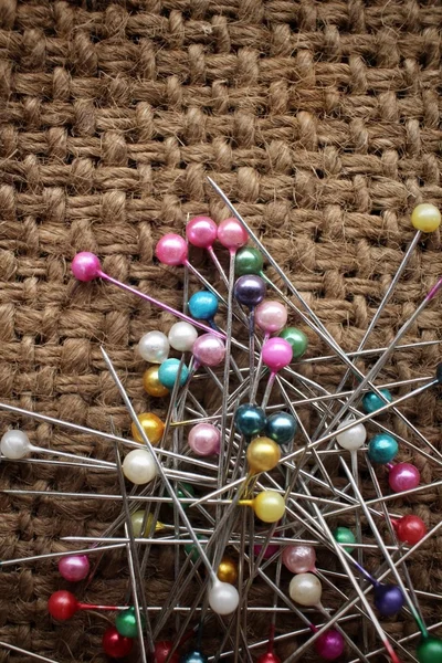 Pinos de costura coloridos em pano de saco — Fotografia de Stock