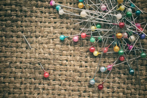 Pinos de costura coloridos em pano de saco — Fotografia de Stock