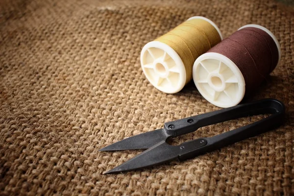 Sewing threads with scissors on sackcloth — Stock Photo, Image