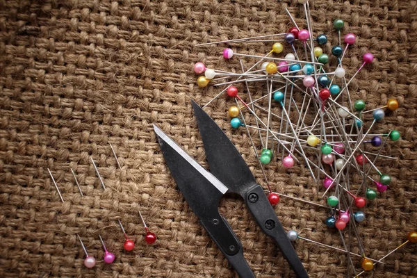 Pinos de costura coloridos com tesoura em pano de saco — Fotografia de Stock