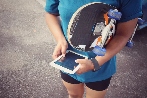 Jong meisje met behulp van Tablet PC met skateboard — Stockfoto