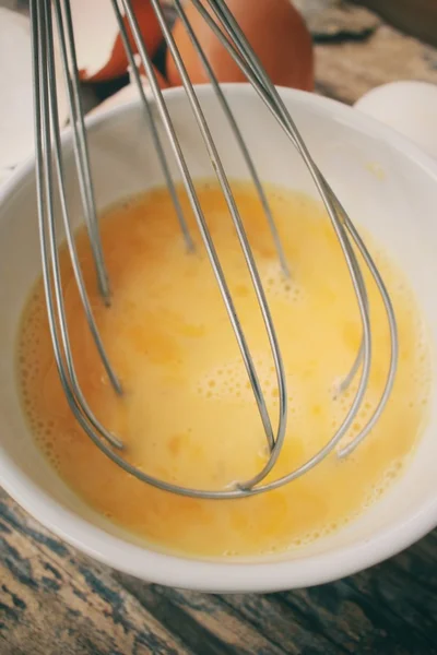 Huevos en un tazón con batidor — Foto de Stock