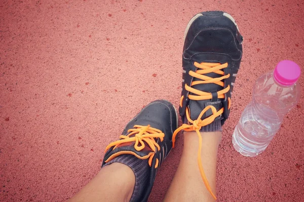 Sapatos esportivos com bebida de água na pista — Fotografia de Stock