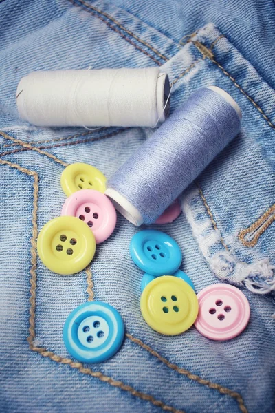 Colorful sewing buttons with thread on jeans — Stock Photo, Image