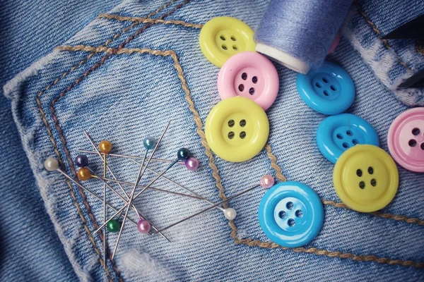 Colorful sewing buttons with thread on jeans — Stock Photo, Image