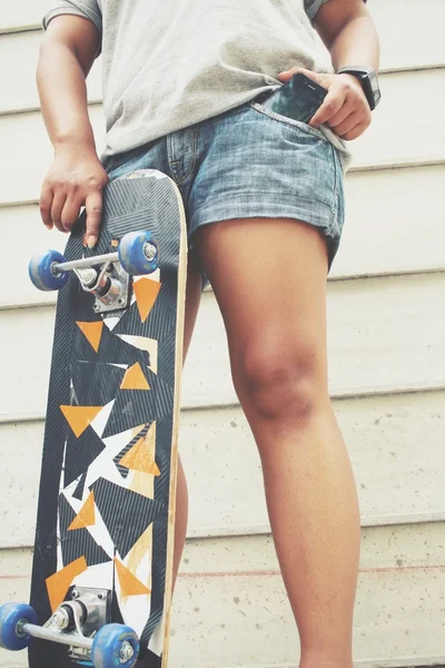 Smartphone in Jeanstasche mit Skateboard — Stockfoto