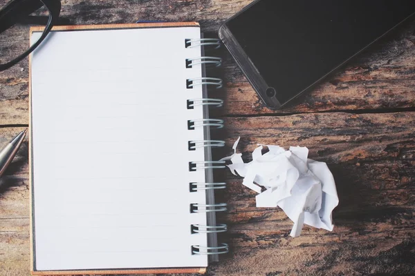 Bloco de notas em branco e telefone inteligente com óculos na mesa de escritório — Fotografia de Stock