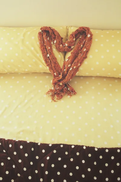 Corazón de la bufanda en almohadas de la cama en el hotel —  Fotos de Stock