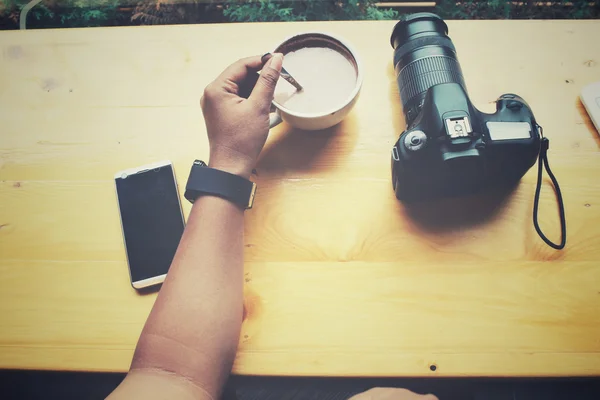 Mujer bebiendo café con teléfono inteligente y cámara — Foto de Stock