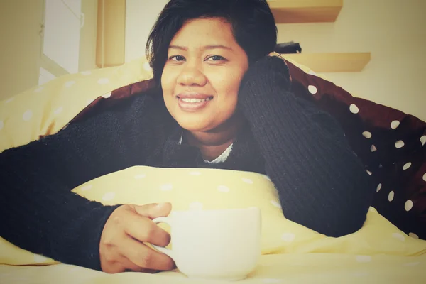 Frau trinkt Kaffee auf dem Bett — Stockfoto