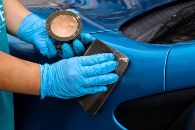 Mavi araç kaputunda mavi eldivenlerle araba cilalama ve cilalama.