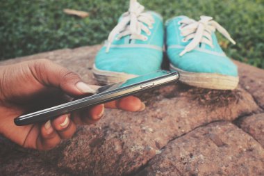 Spor ayakkabıları ile akıllı telefon kullanan kadın