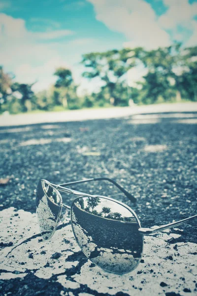 Солнцезащитные очки с отражением и дорогой — стоковое фото