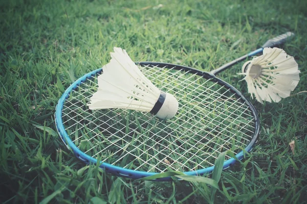 Opeřené s Badmintonové rakety na zelené trávě — Stock fotografie