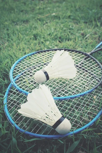 Opeřené s Badmintonové rakety na zelené trávě — Stock fotografie