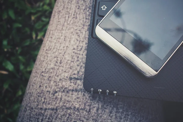 Computadora portátil con teléfono inteligente en la pierna — Foto de Stock