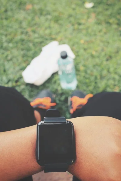 Selfie smartwatch a sportovní obuv s vodou nápoj na zelené trávě — Stock fotografie