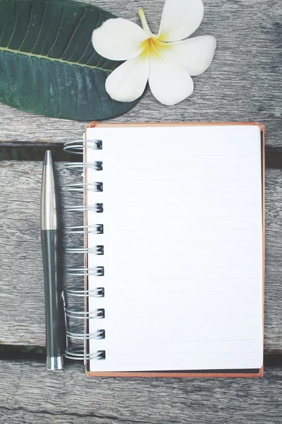 Boş not defteri ve kalem ile frangipani çiçek ofis masaları — Stok fotoğraf