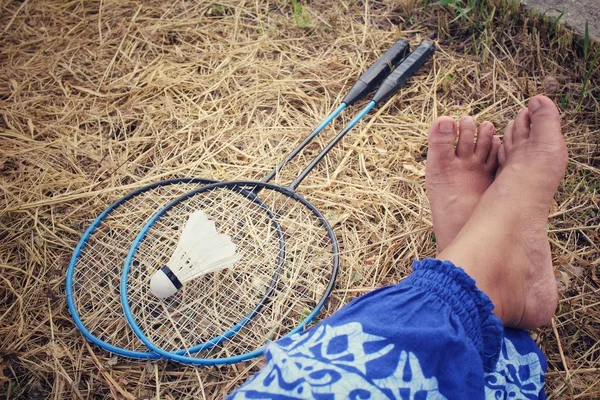 Selfie av fötter med fjäderbollar med badmintonracketen. — Stockfoto