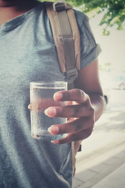 Kadın turist su içmek ve yolda duran sırt çantası ile — Stok fotoğraf