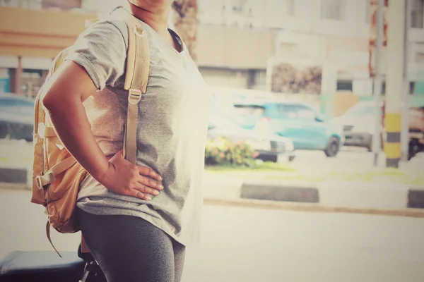 Turista mujer con una mochila de pie en la carretera — Foto de Stock