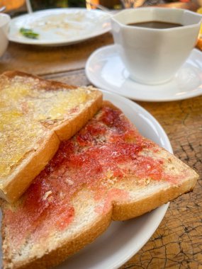 Marmelatlı tost ekmeği, çilek reçeli ve kahve fincanı kahvaltısı.