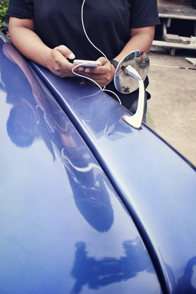 Mujer escuchando música en auriculares con teléfono inteligente y coche viejo — Foto de Stock