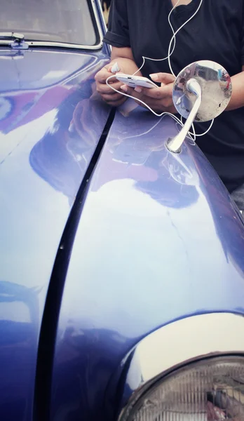 Woman listening to music on earphone with smart phone and old car — Stock Photo, Image