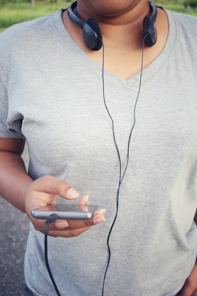 Mulher ouvindo música no fone de ouvido com telefone inteligente — Fotografia de Stock