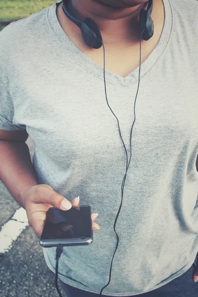 Mulher ouvindo música no fone de ouvido com telefone inteligente — Fotografia de Stock